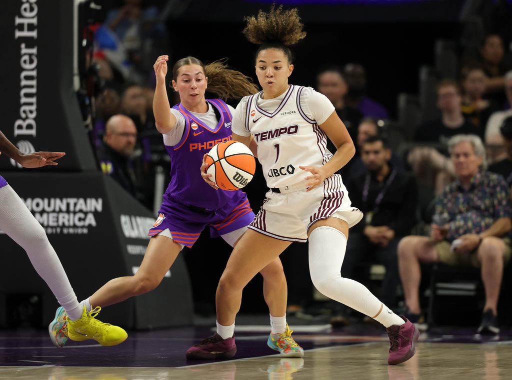 Shay Ciezki in a purple "Phoenix" unifrom and Kiki Rice in a white "Tempo" uniform battle for the ball on court, in an intense game.