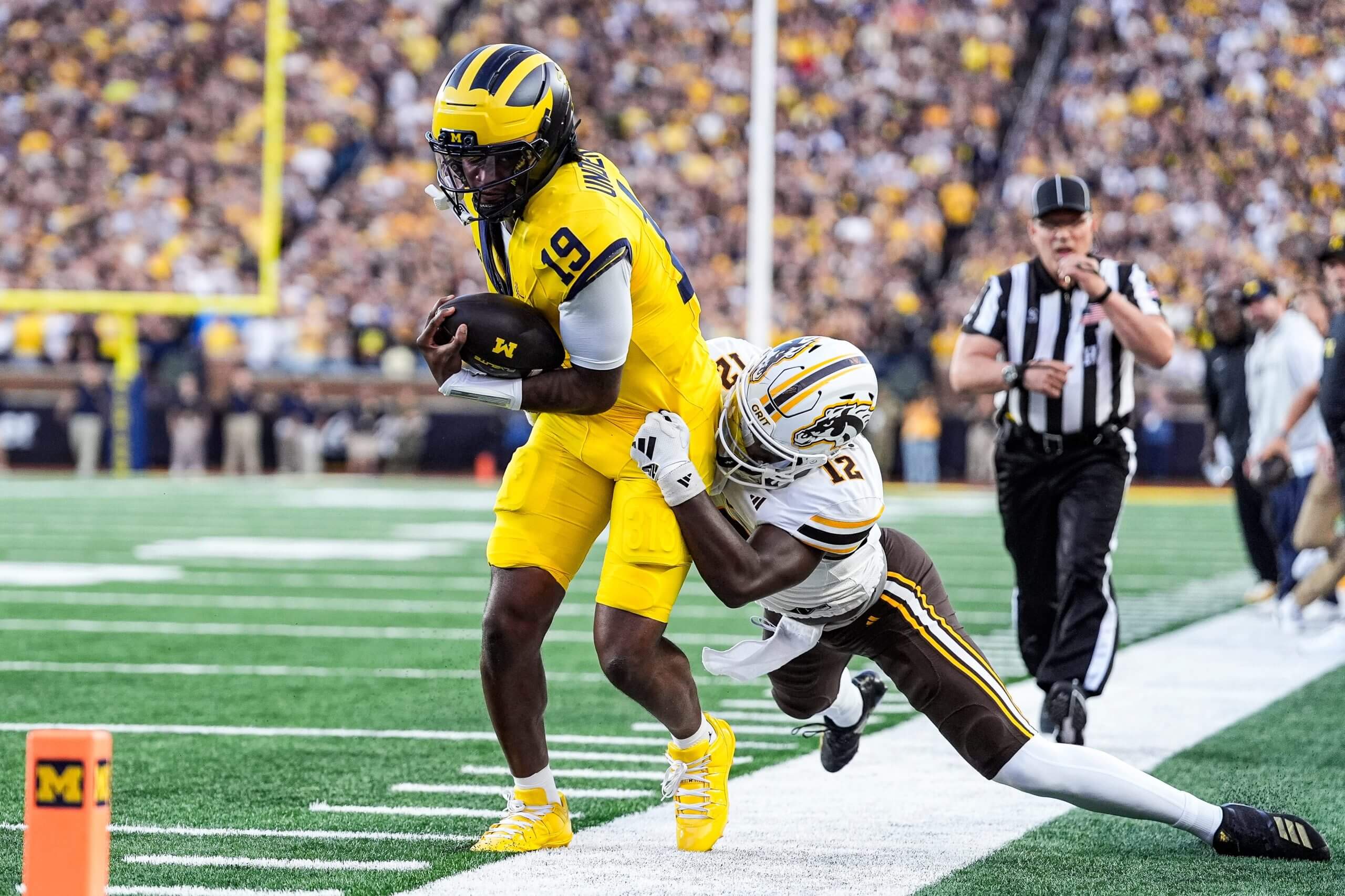 Bryce Underwood runs with the football while being pulled down.