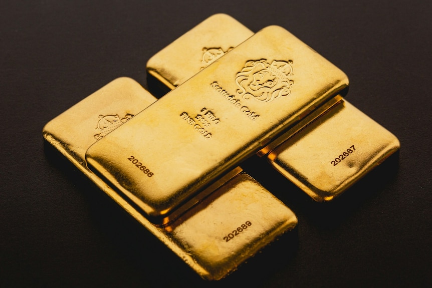 Three gold bars on a dark background, with one bar stacked on a base of two bars.