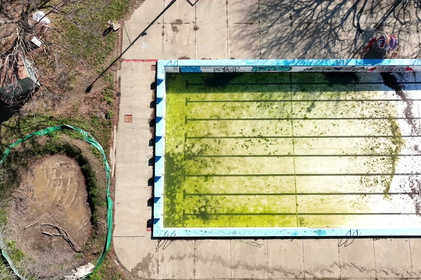 An aerial view of an unclean swimming pool with no water.