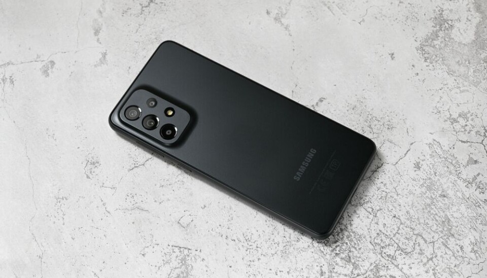 Black Samsung Galaxy A33 (2022) smartphone lying diagonally on a light gray textured surface