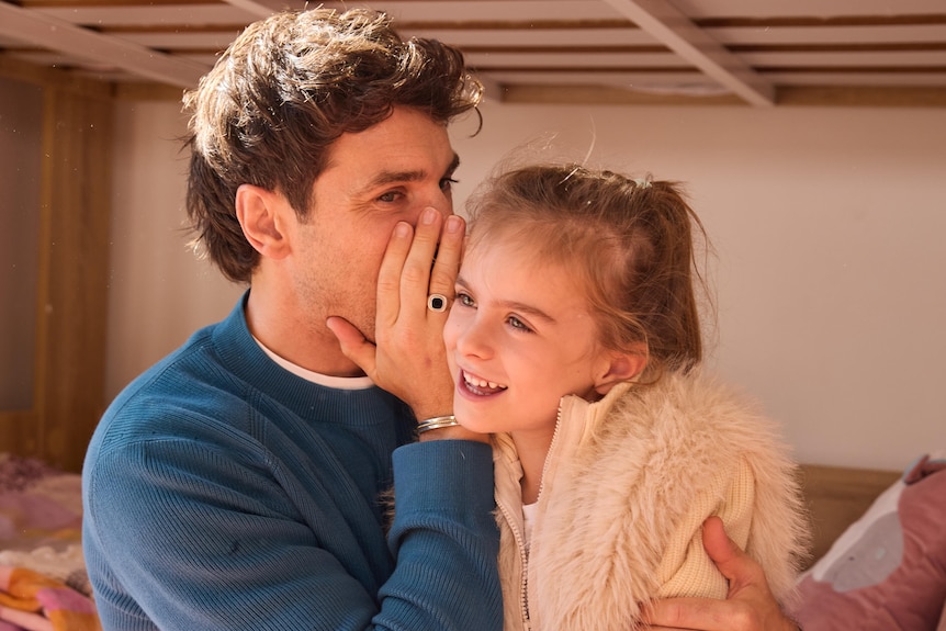A man whispers into his daughter's ear