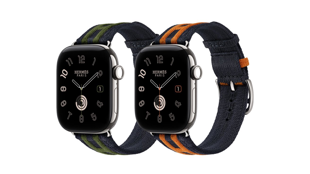 Two Apple Watch Hermes models with black faces and dark fabric bands, one featuring green stripes and the other orange stripes, shown side by side on a white background