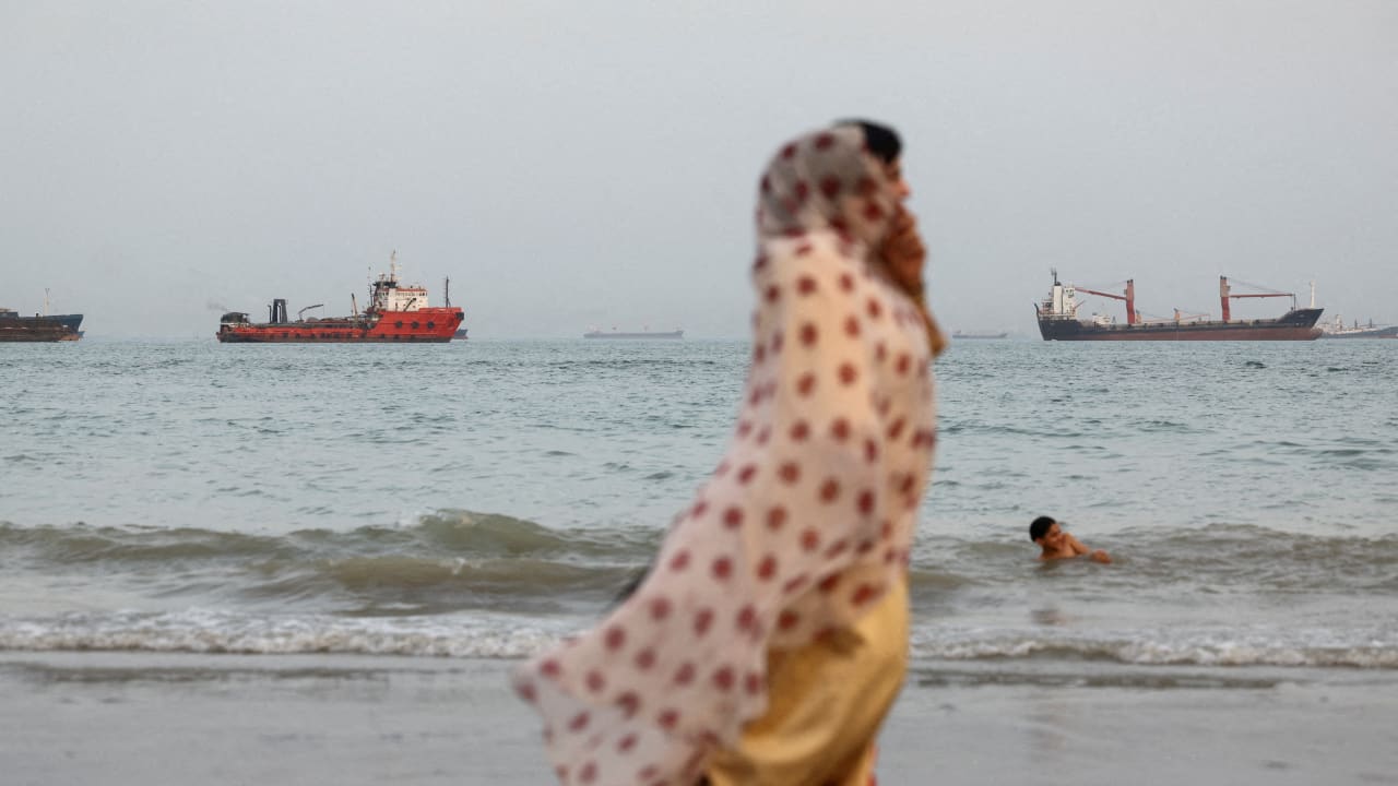 FILE PHOTO: People walk on the beach, with vessels in the Strait of Hormuz visible near the beach of Bandar Abbas, Iran, May 22, 2026.