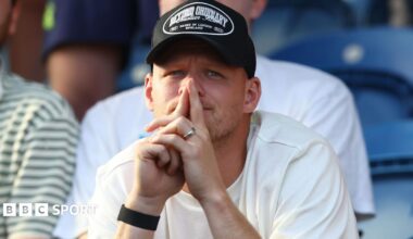 Aaron Ramsdale, wearing a black baseball cap and white t-shirt, watches Southampton's EFL Cup game at Colchester United from the stands