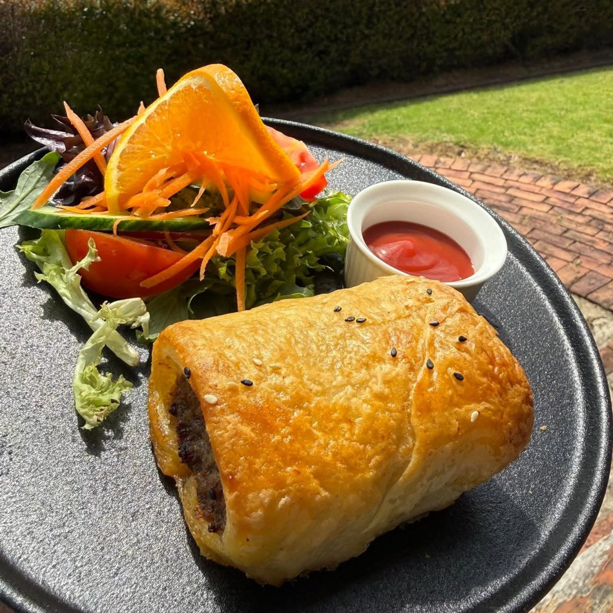 A tasty looking sausage roll with salad on a plate.