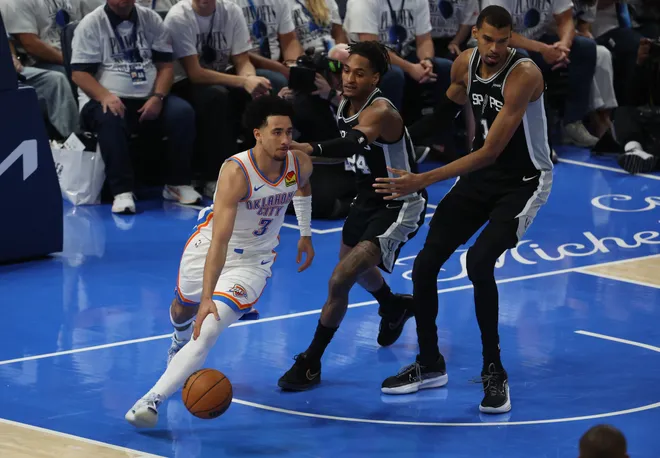 May 26, 2026; Oklahoma City, Oklahoma, USA; Oklahoma City Thunder guard Jared McCain (3) dribbles against San Antonio Spurs guard Devin Vassell (24) and forward Victor Wembanyama (1) during the third quarter in game five of the western conference finals for the 2026 NBA playoffs at Paycom Center. Mandatory Credit: Brett Rojo-Imagn Images