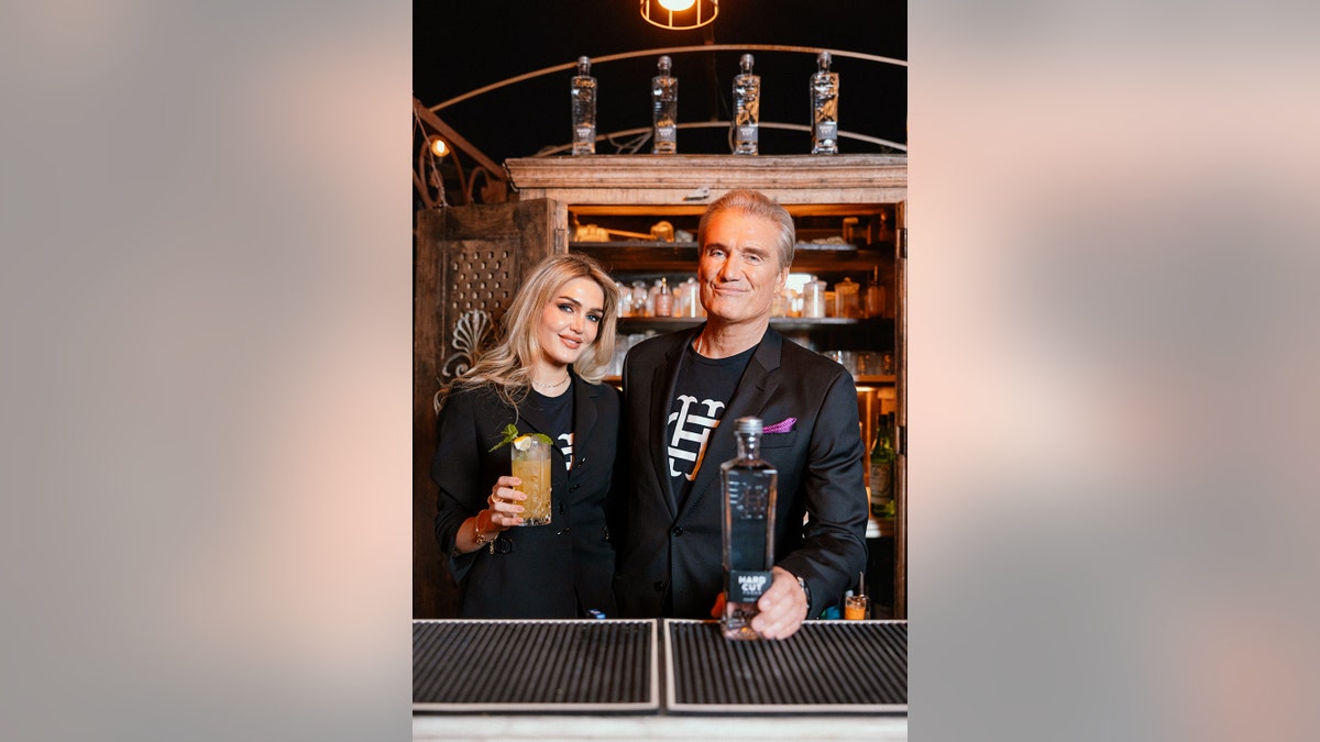 Dolph Lundgren and his wife Emma holding a cocktail behind the bar.