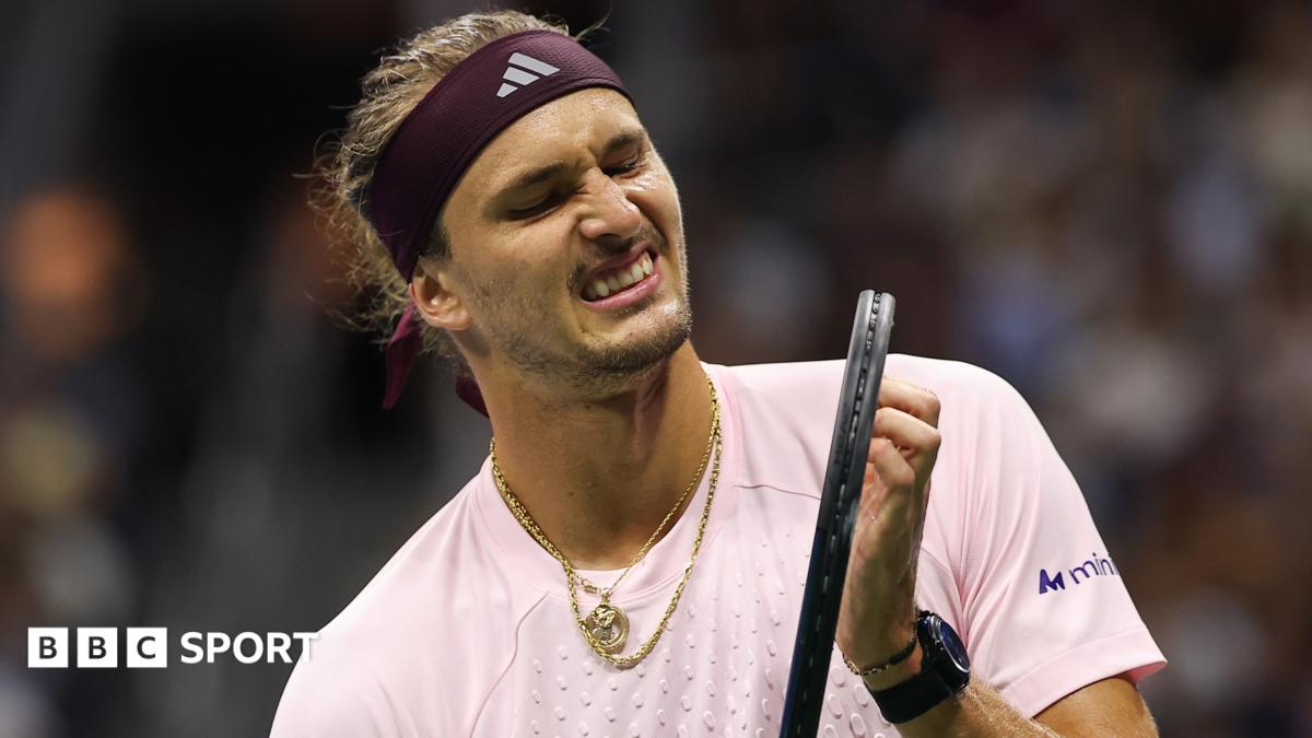 Alexander Zverev, wearing a light pink shirt and with gold jewellery around his neck, grimaces while holding his racquet during his second-round win over Quentin Halys at the US Open