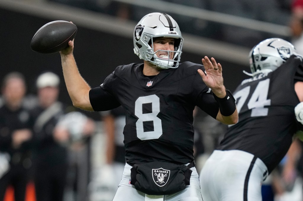 Kirk Cousins in a black Raiders uniform with number 8 on it, preparing to throw a football.