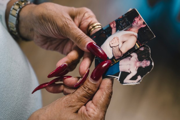 Teresita V. Morales shows pictures of her longtime partner Euġen Cuťa in his younger days before suffering a stroke, Sept. 28, 2026. (E. Jason Wambsgans/Chicago Tribune)