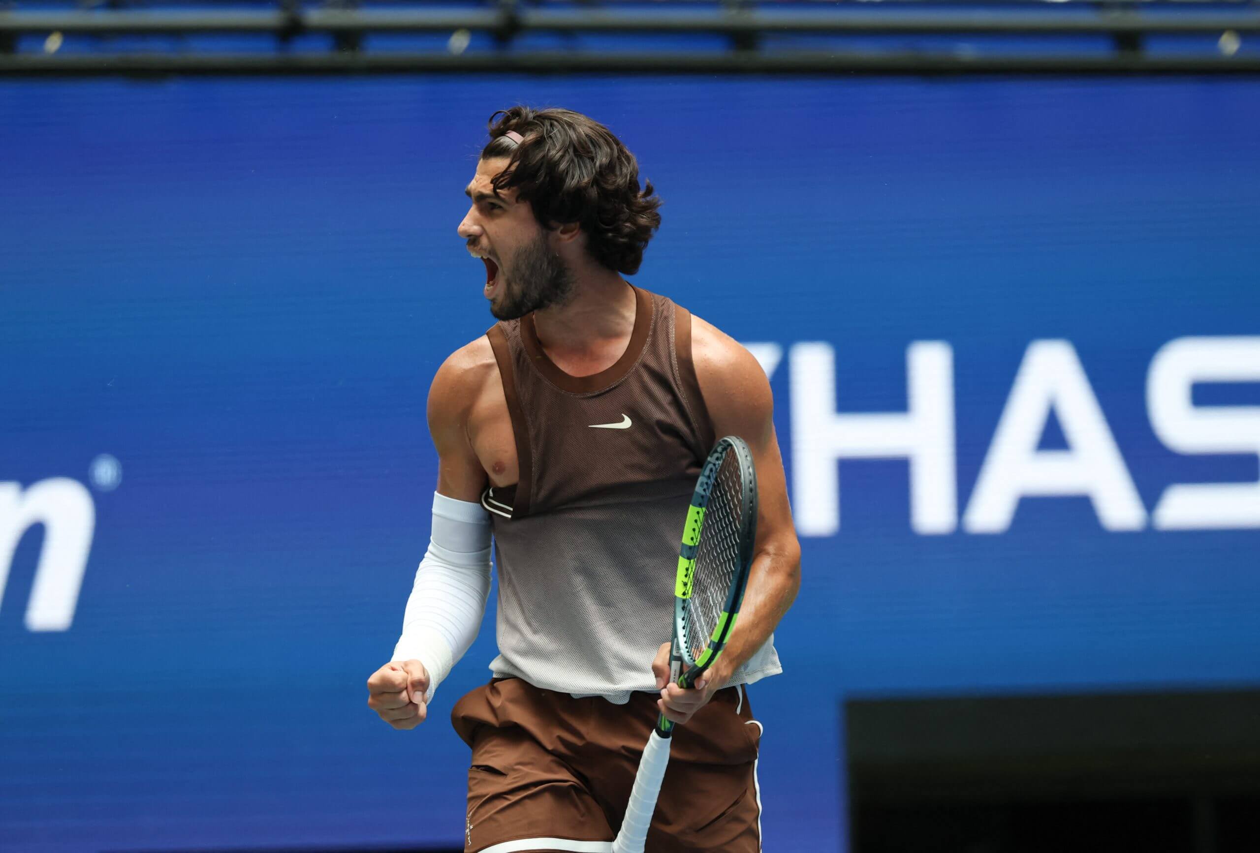 Carlos Alcaraz roars while looking to his right with his right nipple showing.