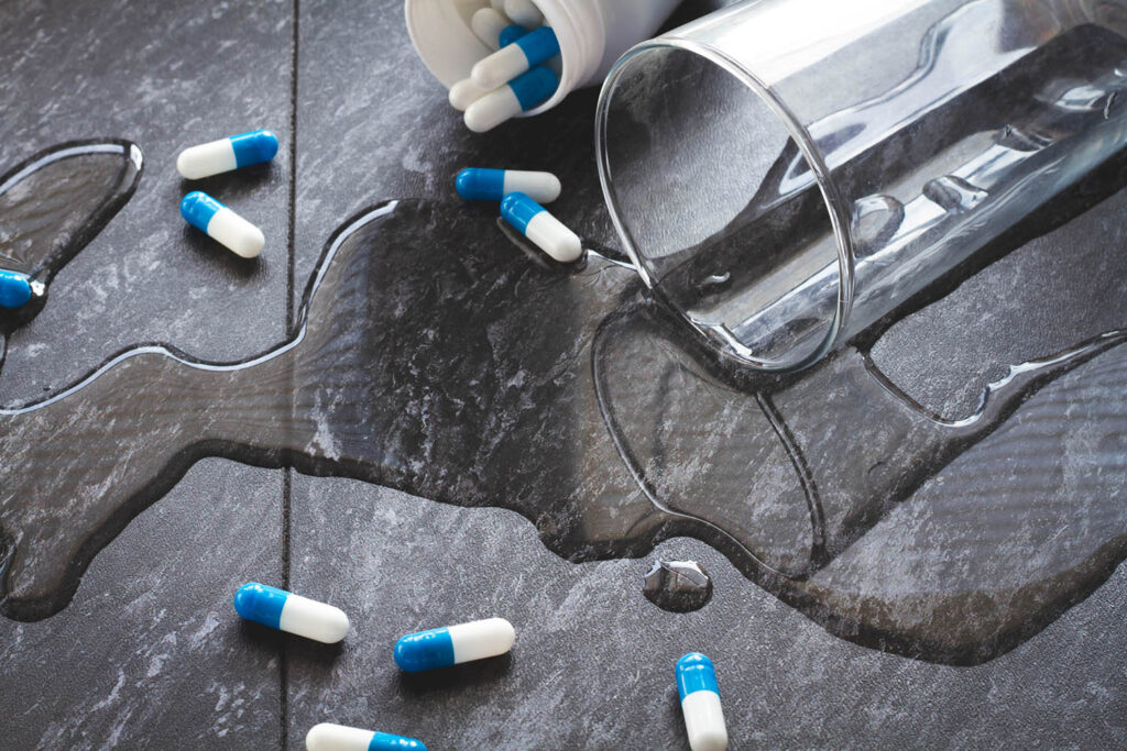 Water is spilled and medical capsules are scattered
