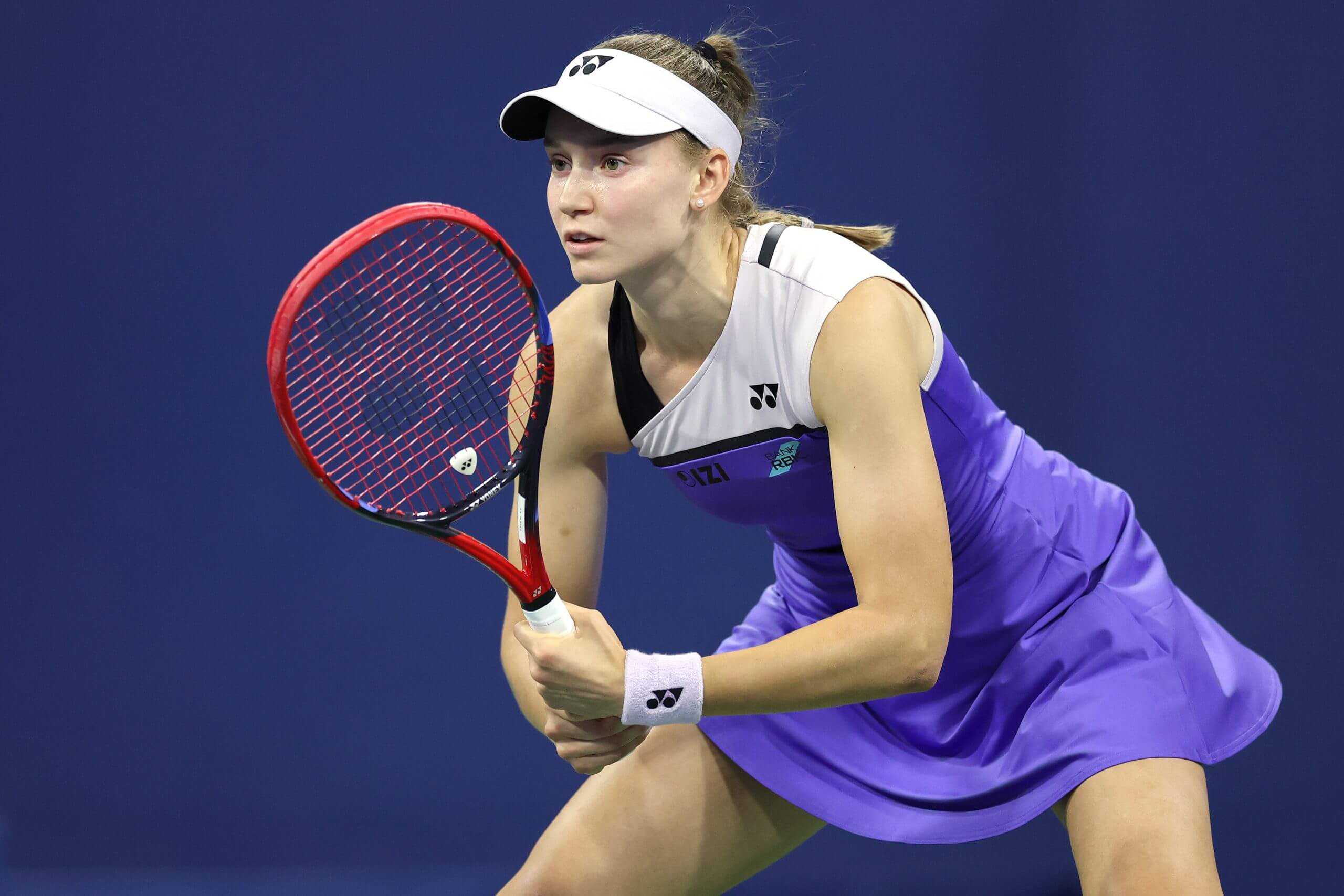 Elena Rybakina looks on wearing a purple kit.