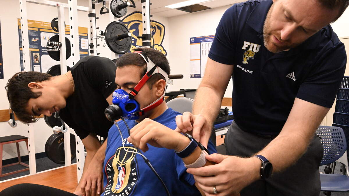 From left, Gabriel Cabeda Ramirez, a bachelor's student in sport and exercise science; teaching and learning kinesiology Ph.D. student Daimien Campos; and FIU researcher Jason Kostrna, associate professor of kinesiology and exercise science, participate in a demonstration of the study protocol on Friday, Aug. 21, 2026, at Florida International University in Miami. Cabeda Ramirez and Kostrna reviewed readings from four smartwatches worn by Campos as he rode a stationary bike. The study evaluated how accurately popular smartwatches estimate calories burned during exercise.