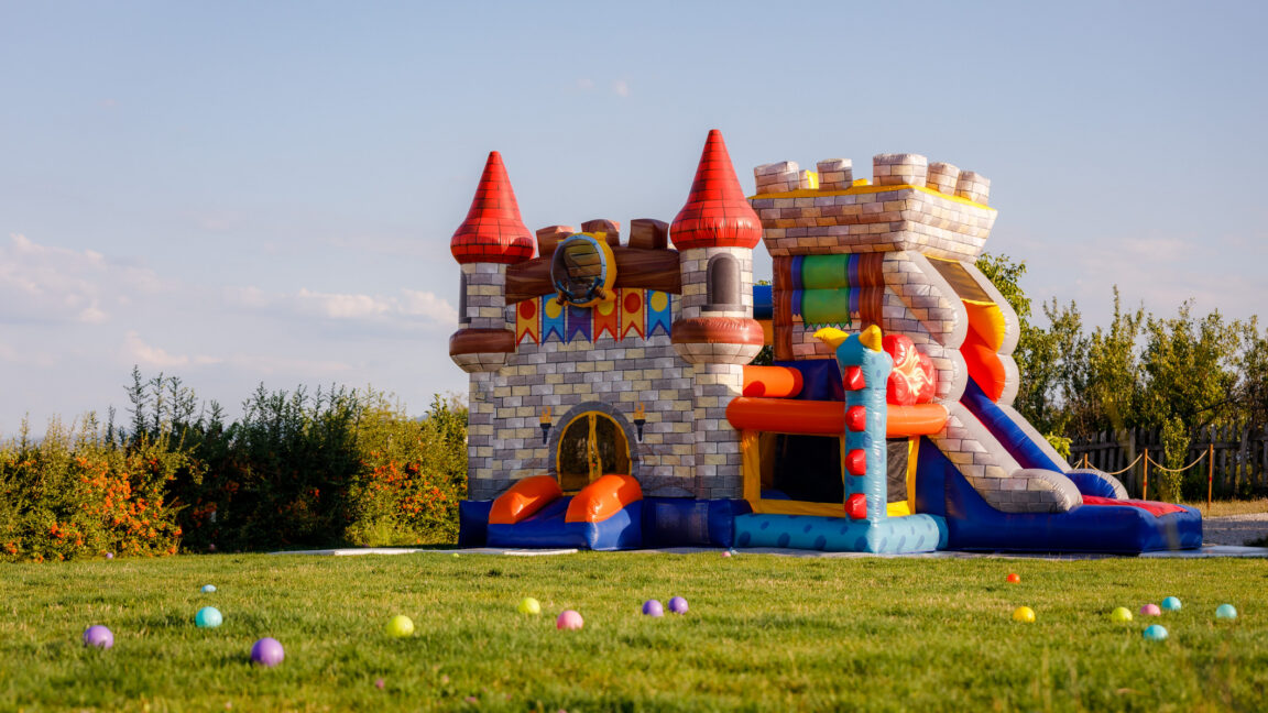An inflatable castle bounce house sits in green field.