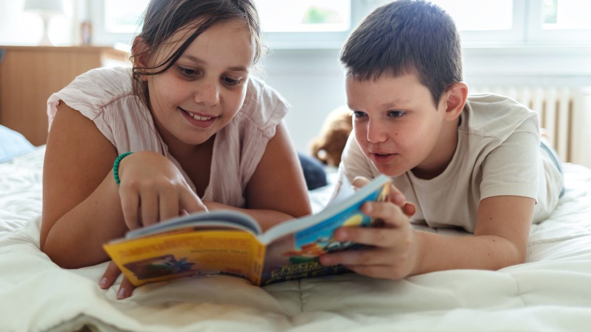 Boy, sister and reading book on sofa house for knowledge, bonding and learning literature, fantasy and language development. Family, girl and storytelling, education and information of child growth. - stock photo