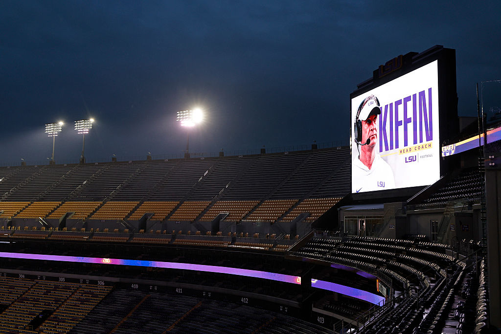 A stadium at night with the lights on and a Lane Kiffin sign featuring his name and photo.