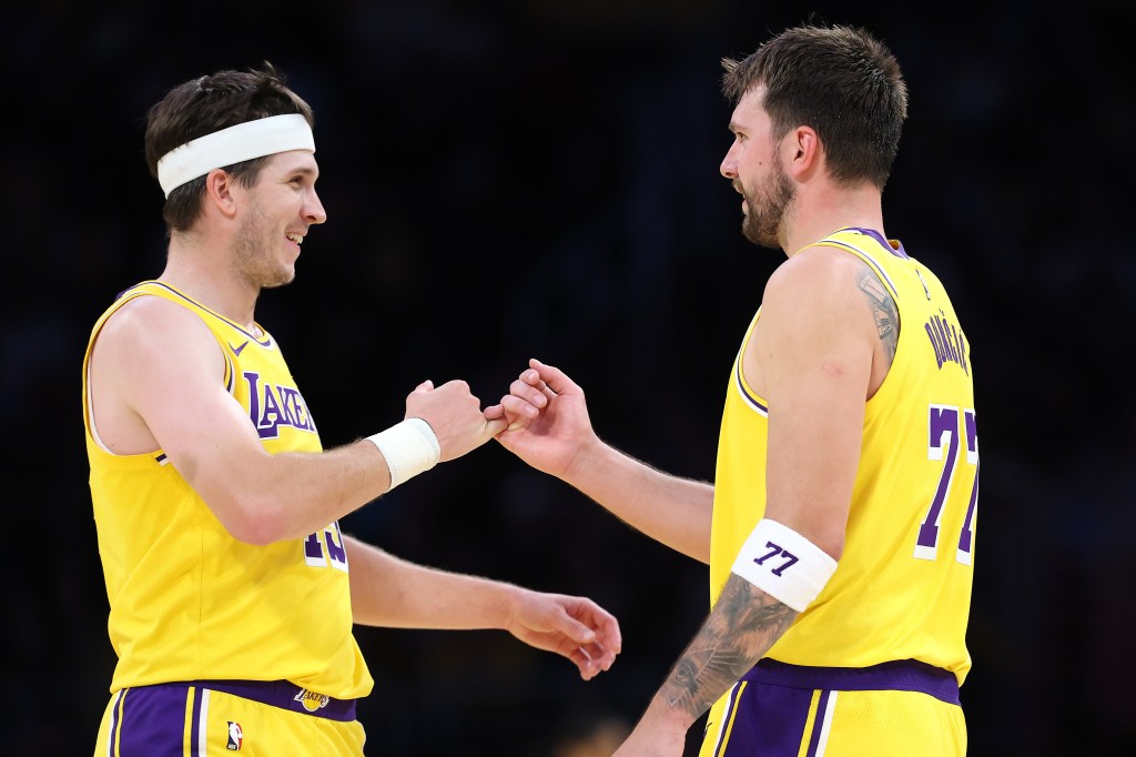 Two basketball players in yellow jerseys, one with a headband, link pinkies.
