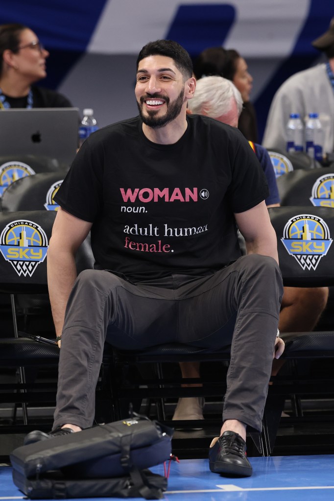 Enes Freedom smiling while wearing a black t-shirt that reads "WOMAN noun. adult human female."