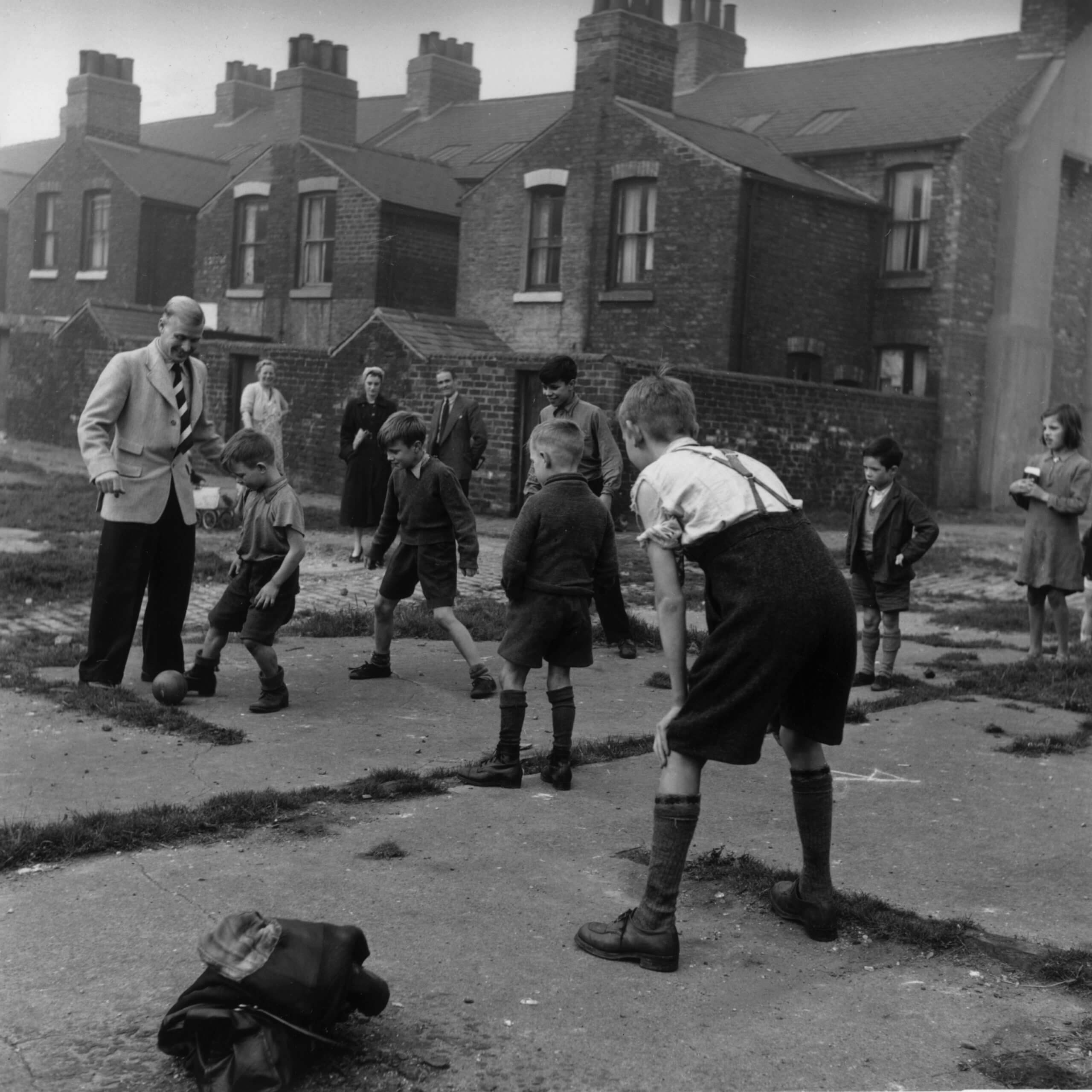 Wilf Mannion joins a group of youngsters to play football in the street in November 1951