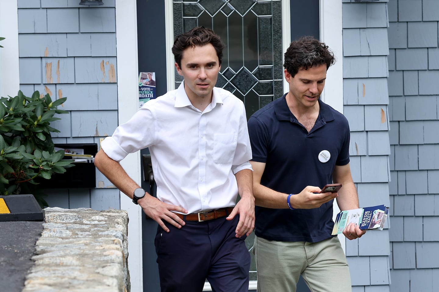 Gun control activist David Hogg, left, leaves a Roslindale home while canvassing in support of Eighth Congressional District candidate Patick Roath, right, on Aug. 30, 2026.  
