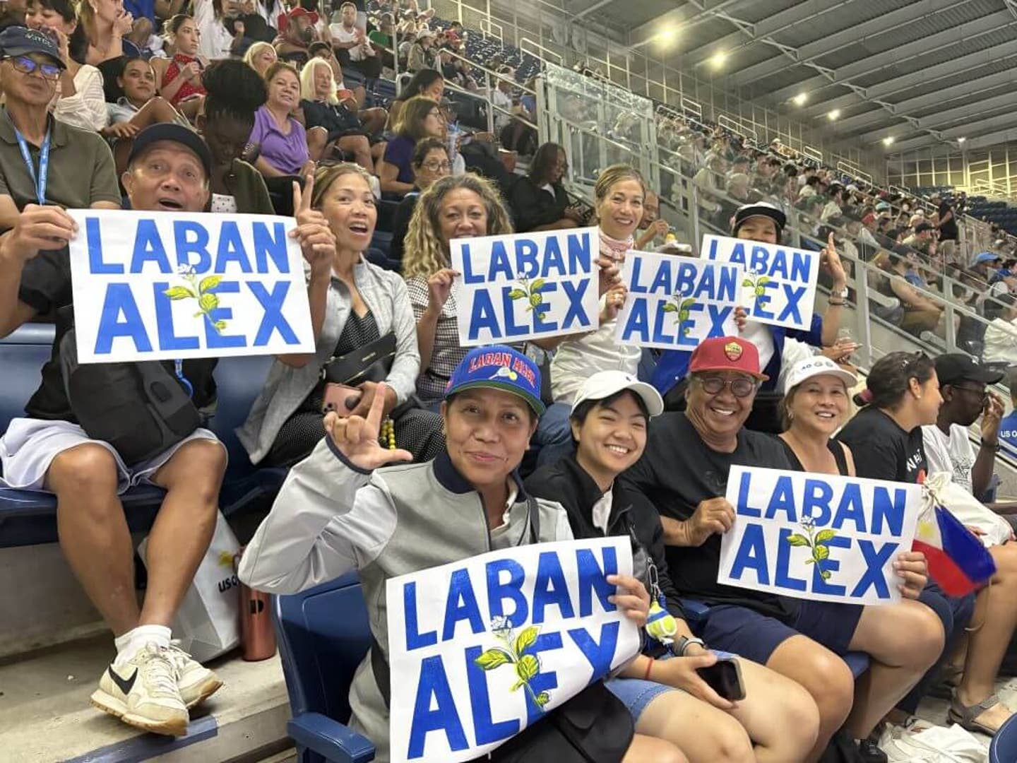 Alex Eala fans hold up posters with the phrase 