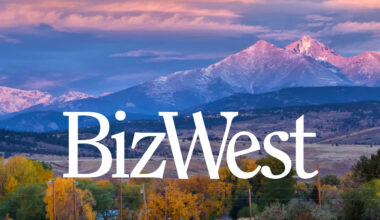 A white version of the BizWest logo, superimposed atop a beautiful photo of Longs Peak and Mount Meeker.