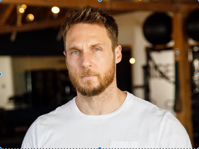 man wearing a white tshirt facing the camera from chest up