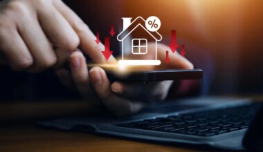 Businessman use smartphone with virtual home icon and down arrow for economical real estate and lower mortgage interest rates. Reduced prices for rental housing, Demand for home purchases decreases.