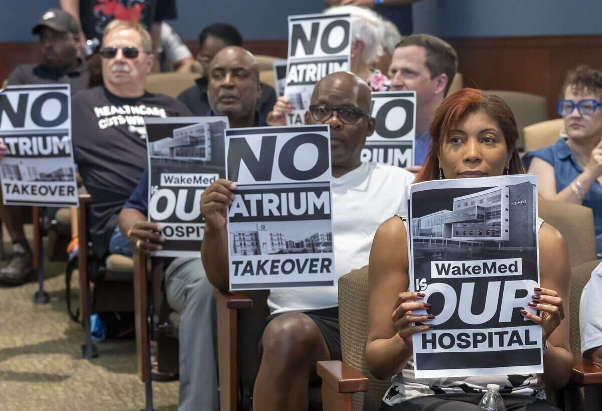 Opponents of a proposed merger between WakeMed and Atrium Health display their opposition, prior to the Wake County Commissioners meeting on Monday, July 6, 2026 in Raleigh, N.C.