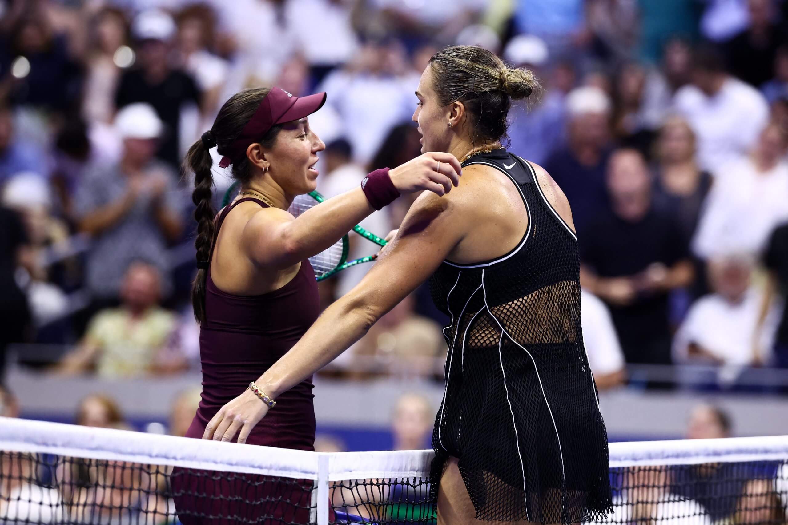Jessica Pegula hugs Aryna Sabalenka over a tennis net.