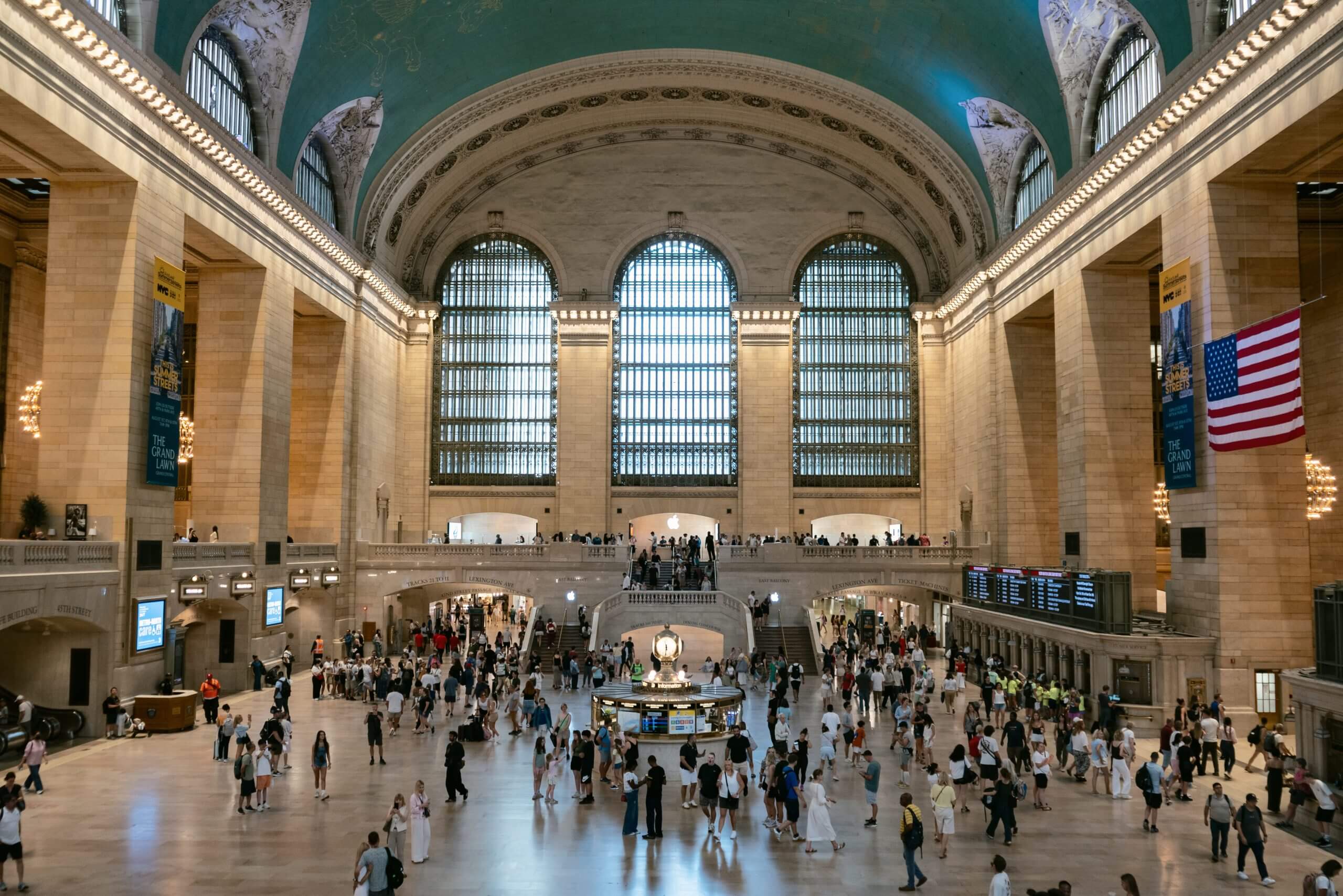 Inside Grand Central Terminal's main concourse, with Beaux-Arts décor and people clustered around the clock at its center.