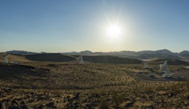 several antennas sit under a blue sky and blazing sun.