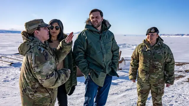 JD Vance and his wife Usha Vance pictured with the commander of the US military's Pituffik Space Base in Greenland in March. They are surrounded by a snowy landscape.