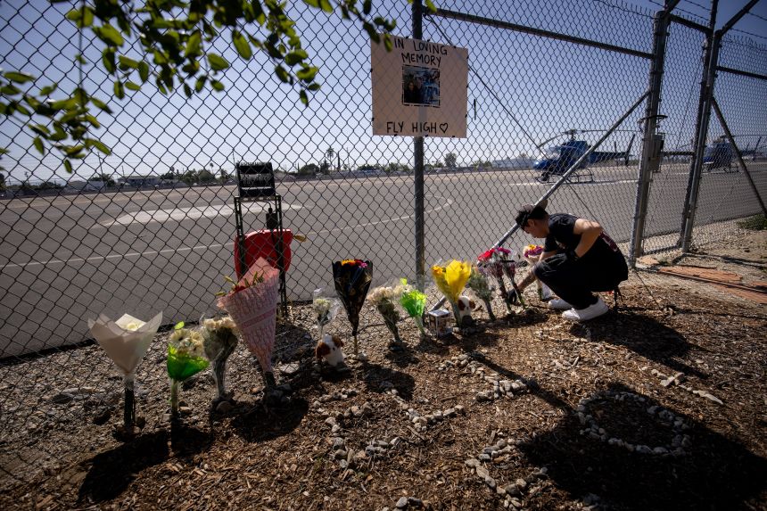 A person adjusts flowers on September 16 at a memorial for Eliana Moreno and George Marciniw, who died in a helicopter crash the day before.