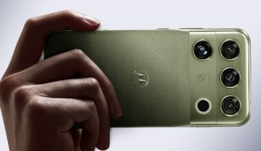A hand holds a green smartphone with a triple-lens camera system and a Motorola logo on the back.