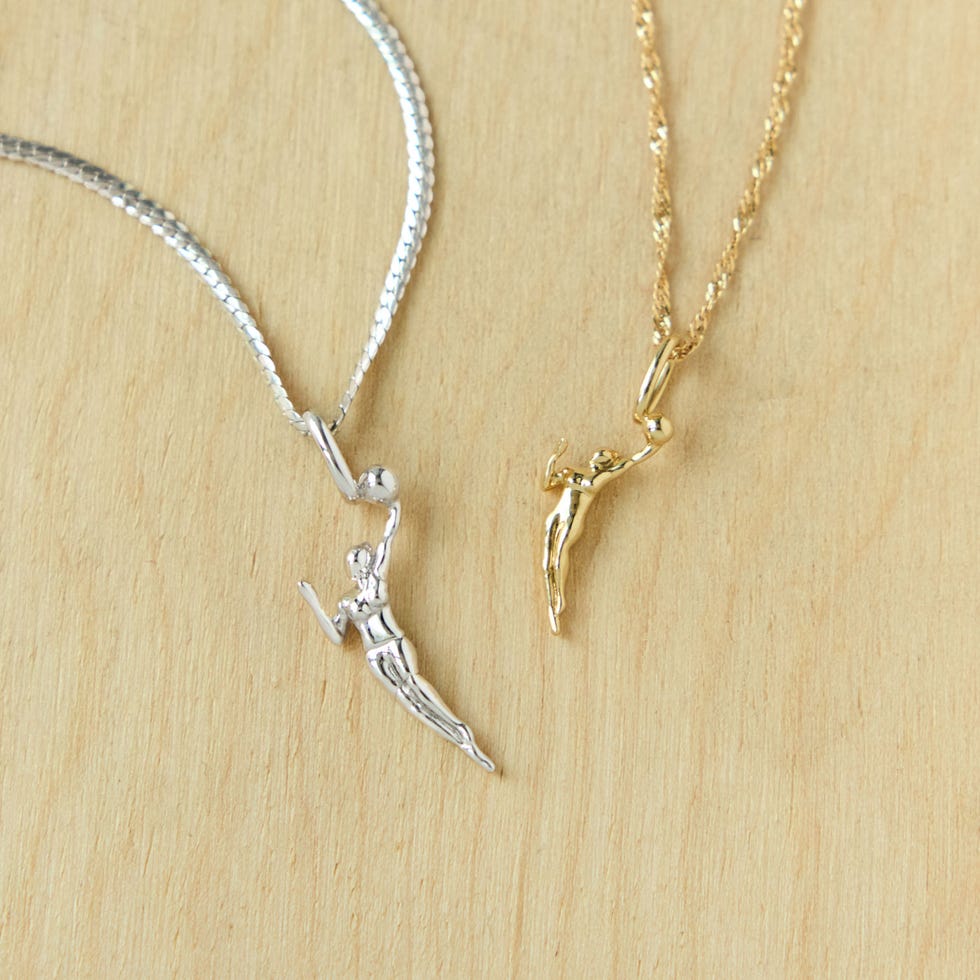 Two basketball player pendants in silver and gold on a wooden surface. Two basketball player pendants in silver and gold on a wooden surface.