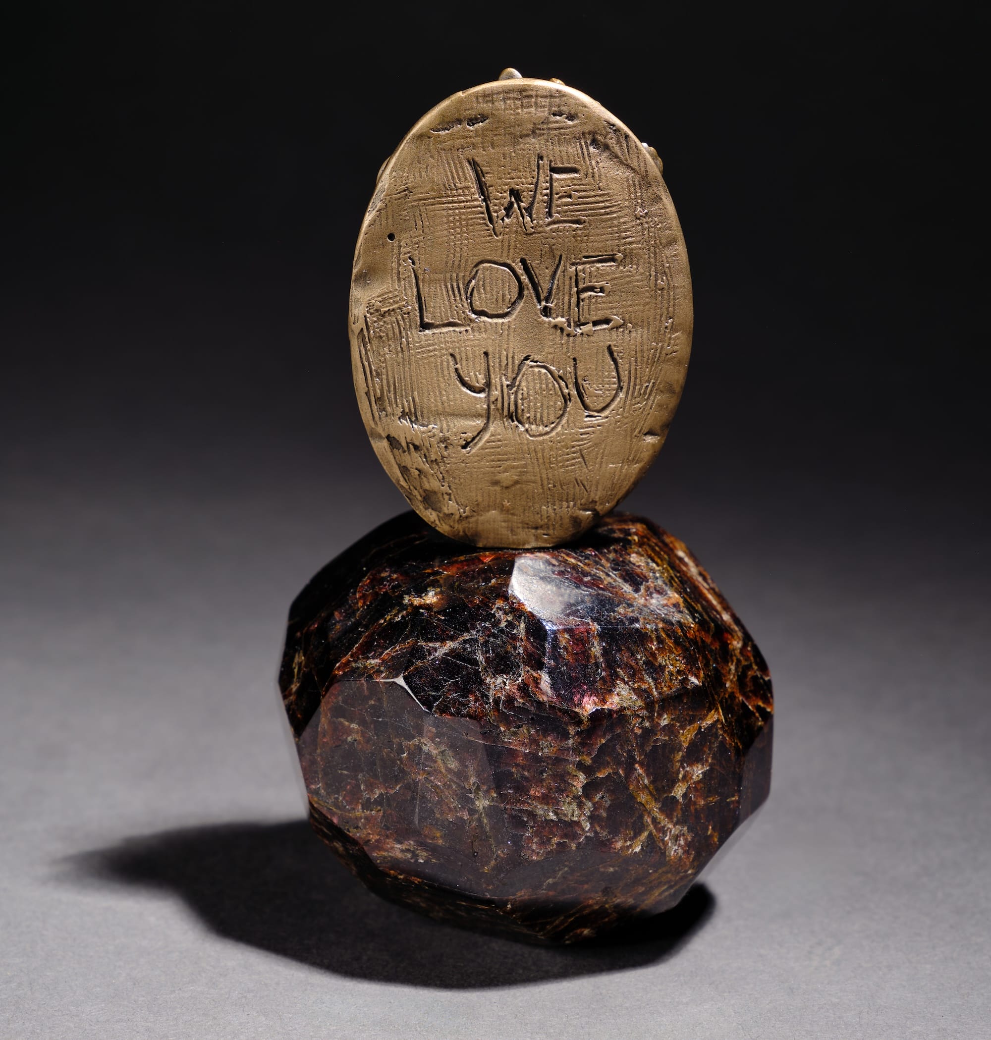a small sculpture of a bronze pendant that reads