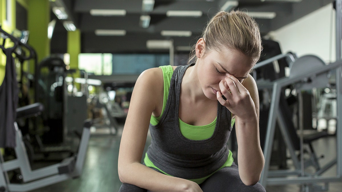 Young woman having headache after working out in a health club