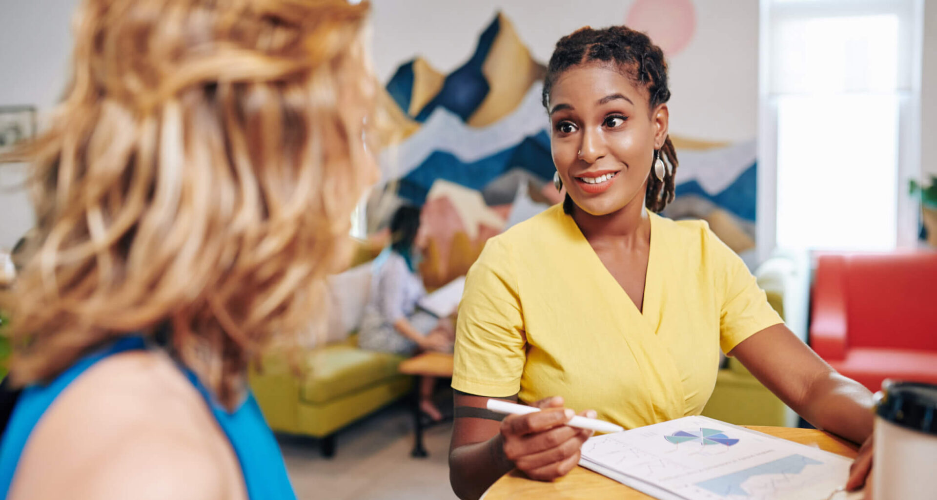 This is an image of two women meeting at a table and reviewing graphs/charts.