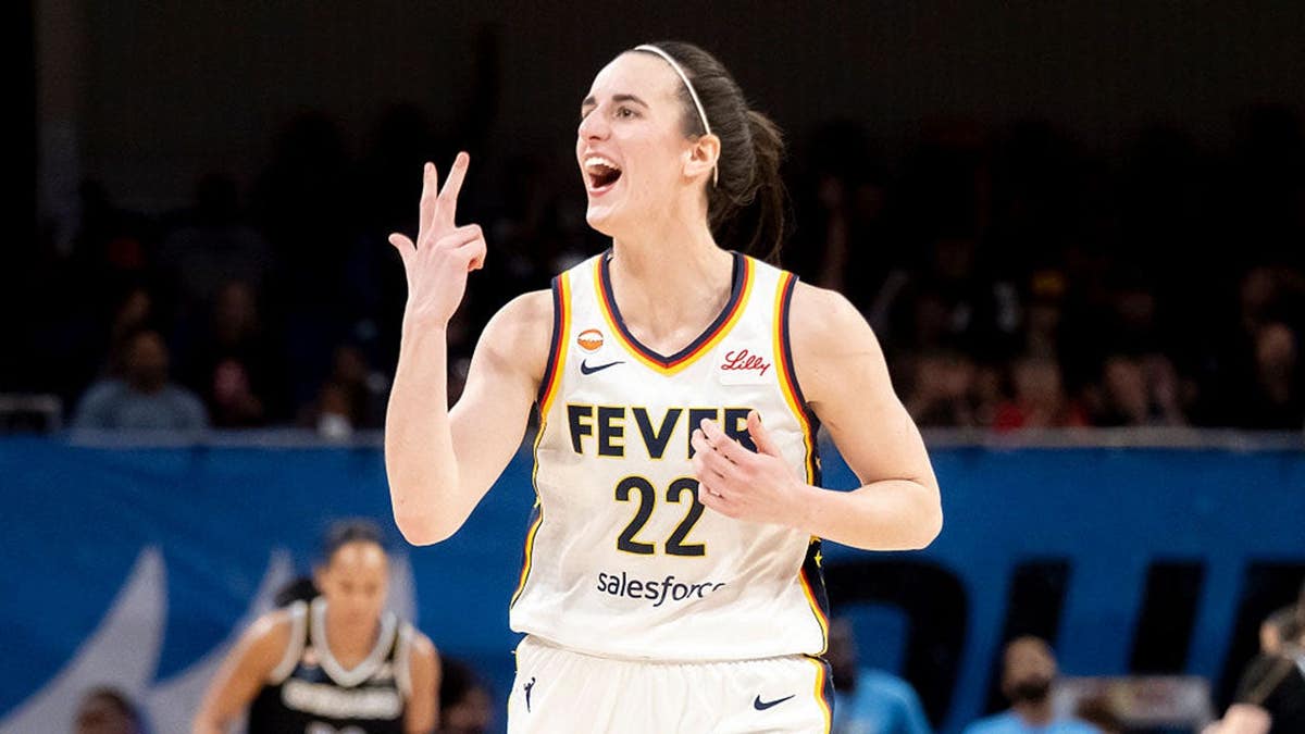 Caitlin Clark reacts after making a 3-point shot during a WNBA game.