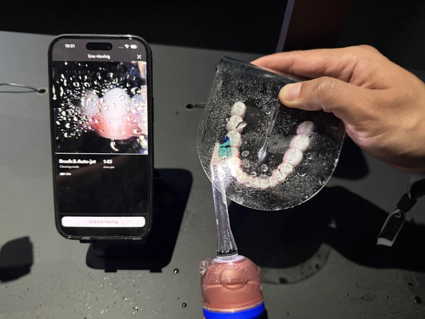 The Dyson CameraJet toothbrush being used to brush fake teeth during a demonstration.
