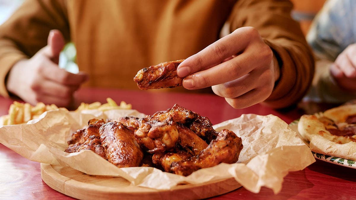 A man eats wings from a plate.