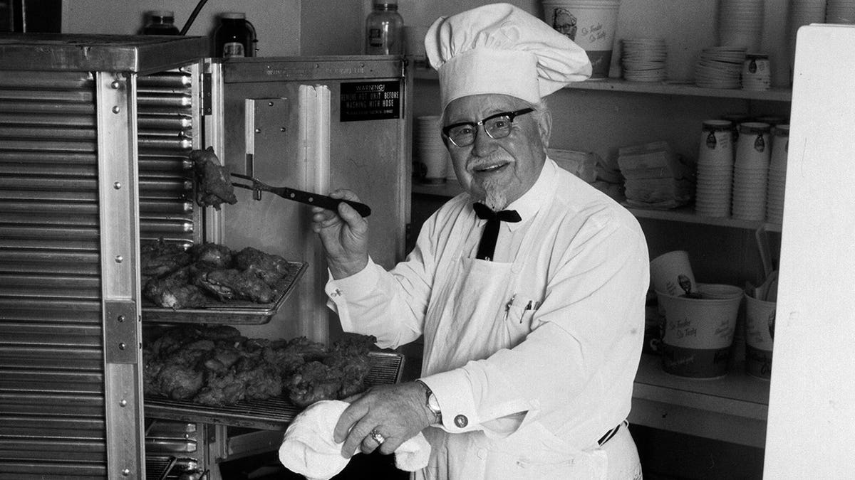 Colonel Harland David Sanders cooking fried chicken in a kitchen.