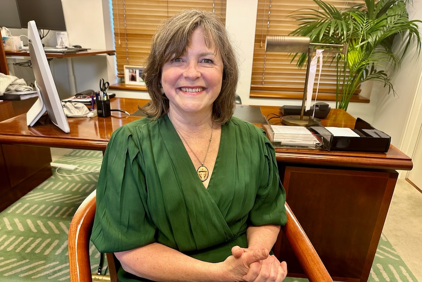 A woman in a green dress sits in her parliament house office