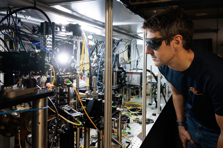 A researcher wearing eye protection looks at the bright glowing light emitted from the lutetium ion clock.