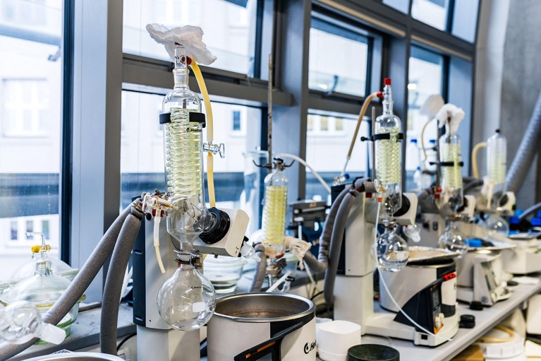 Rotary evaporators with condensers on a lab table in front of a wall of windows.