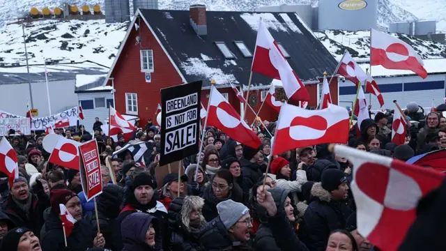 People bear Greenlandic flags as dem gada for di front of US consulate for Nuuk, Greenland, during one protest against President Donald Trump announced intent to acquire Greenland for January 2026