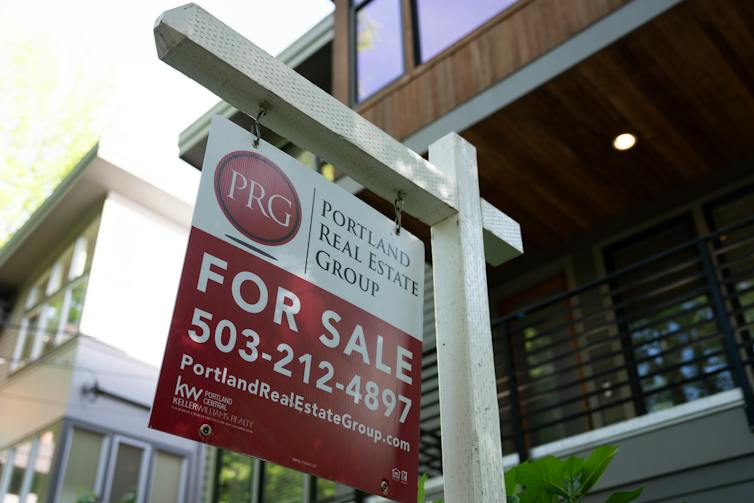 A red and white 'for sale' sign is displayed outside a home in Portland, Ore.